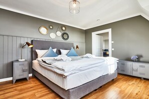 A bedroom with a bed, bedside tables, a dresser, and wall decorations. - Holiday apartment in Hörnum with Wi-Fi (Hörnum)