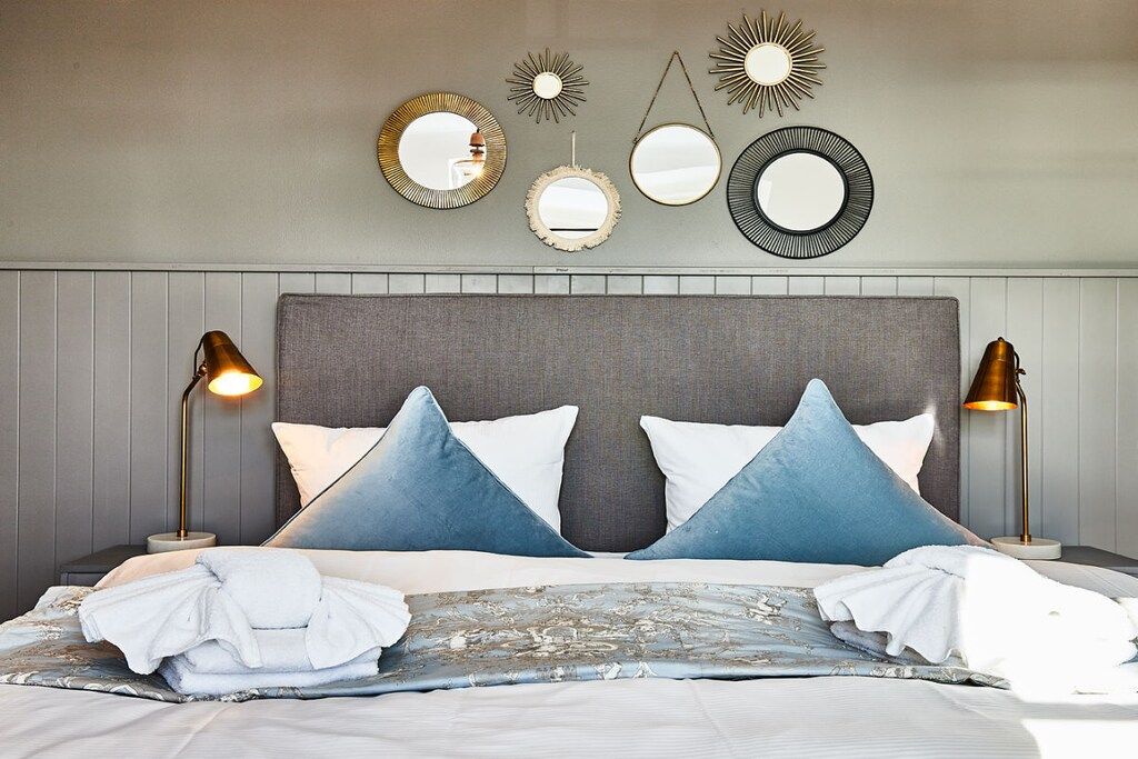 A hotel room with a bed, two bedside lamps, and wall-mounted mirrors.