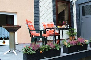 An outdoor seating area with two chairs and a table, surrounded by potted plants. - Holiday apartment with 1 bedroom (Steinbach-Hallenberg)