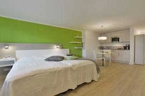 A modern bedroom with a large bed, a bedside table, and a small desk with a chair. - Holiday apartment with 1 bedroom (Breege\/Juliusruh OT Juliusruh)