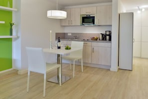 A modern kitchen with white cabinets, a stainless steel microwave, and a white refrigerator. - Holiday apartment with 1 bedroom (Breege\/Juliusruh OT Juliusruh)