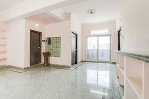 A spacious hallway with a marble floor, a wooden door, a decorative wall piece, and a large window with a view.