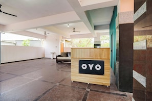 A spacious lobby with a reception desk labeled 'OYO,' a ceiling fan, and a view of the outdoors.
