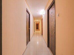 A hotel corridor with doors on both sides, a tiled floor, and a light fixture on the ceiling. - HOTEL O New R Inn (Hyderabad)