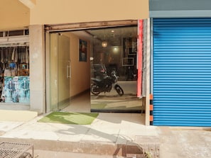A storefront with a glass door, a blue shutter, and a green mat at the entrance. - HOTEL O New R Inn (Hyderabad)