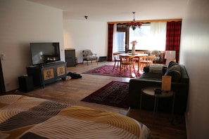 Ett vardagsrum med tv, soffa, matbord och stolar.