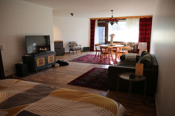 A living room with a television, sofa, dining table, and chairs. - Holiday apartment with 1 bedroom (Füssen)