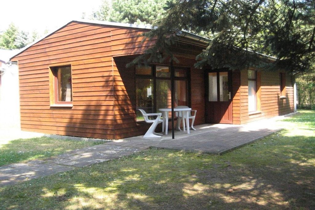 A small wooden cabin with a patio area, a table, and chairs.