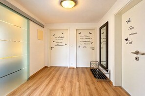 Un corridoio con pavimento in legno, due porte decorate con farfalle e uno specchio sulla parete destra.