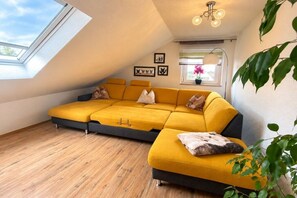 Un soggiorno moderno con un divano componibile giallo, un lucernario e una lampada a sospensione.