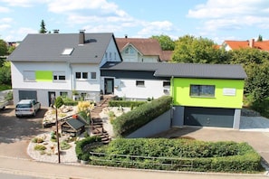 A two-story residential building with a garage, a driveway, and a landscaped garden. - Holiday apartment with 2 bedrooms (Beuren)