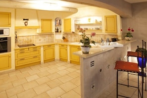A kitchen with yellow cabinets, a central island, and a microwave. - with pool in the beautiful Luberon - 611 JOU (Joucas)