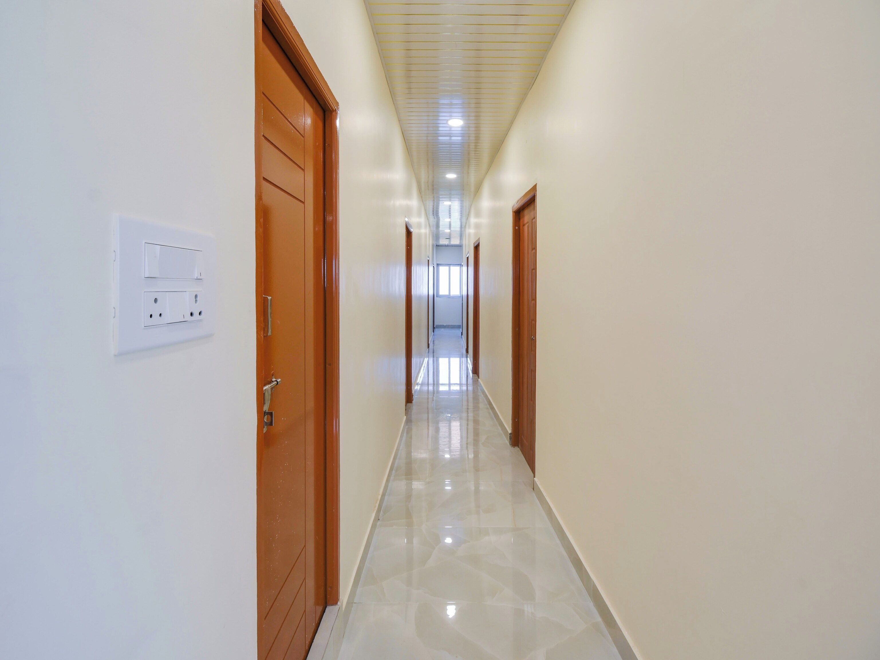Un corridoio con porte su entrambi i lati, un interruttore sulla parete sinistra e un soffitto con faretti.