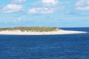 A coastal landscape with a lighthouse, sandy beach, and grassy dunes. - House Gotland 3A 1st floor/attic (Sylt\/ Westerland)