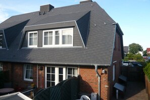 A two-story house with a sloped roof, a brick exterior, and a visible garage door. - House Gotland 3A 1st floor/attic (Sylt\/ Westerland)