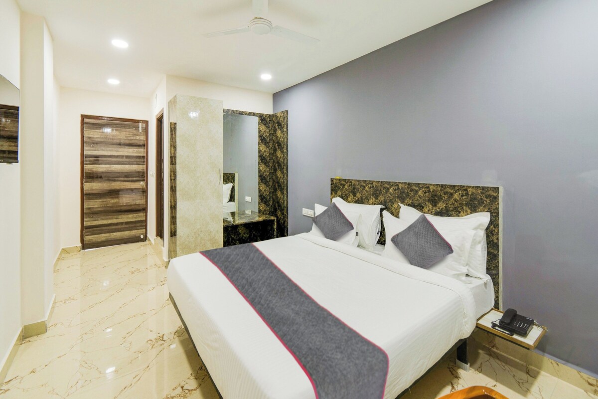 A hotel room with a large bed, a bedside telephone, and a marble floor.