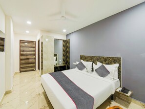 A hotel room with a large bed, a bedside telephone, and a marble floor. - Townhouse Rio (Hyderabad)