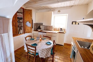 A small, cozy kitchen with a round dining table, wooden chairs, and a window providing natural light. - Cabin with 2 bedrooms (Saint Saturnin lès Apt)