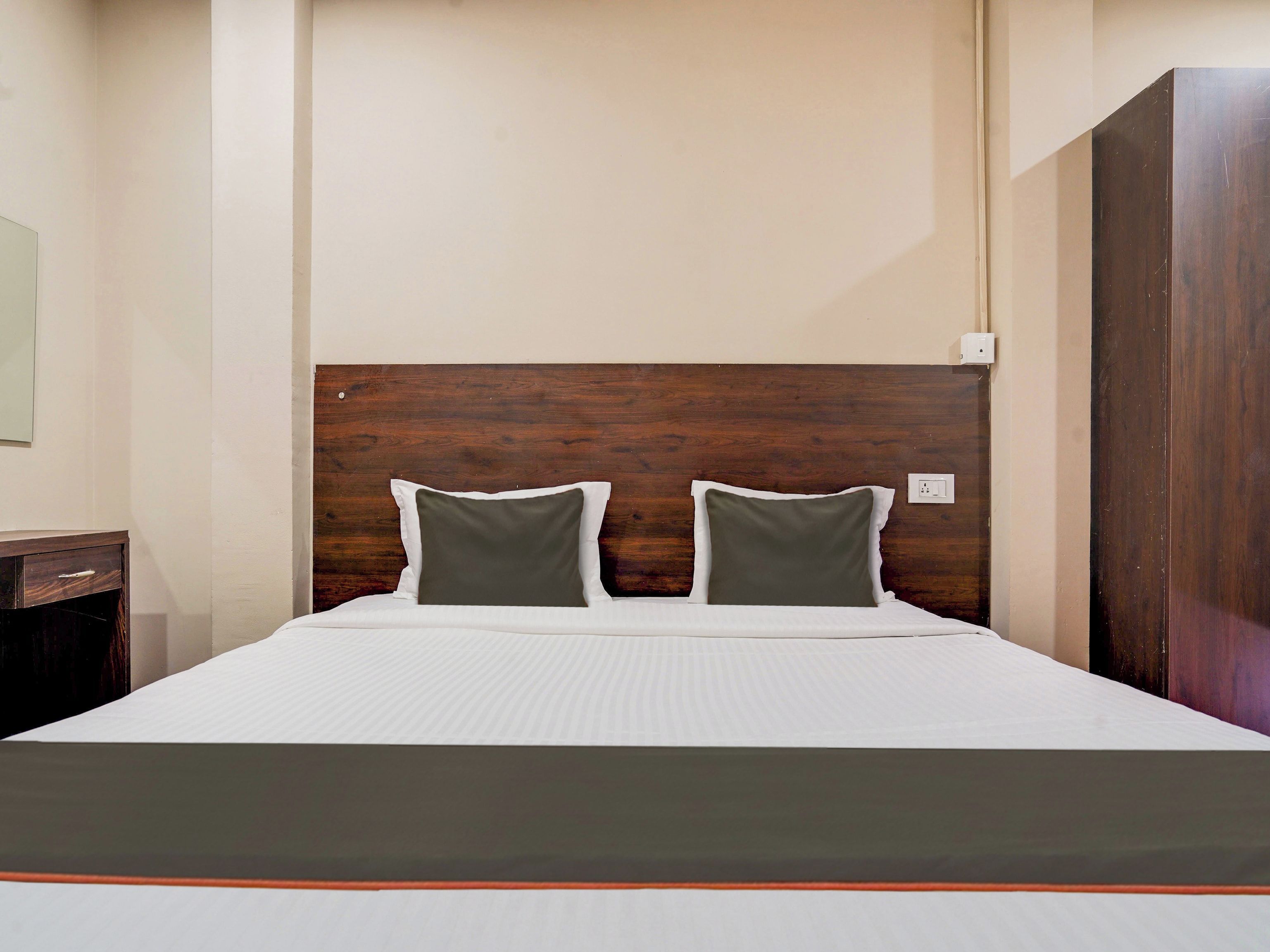 A bed with a wooden headboard, two pillows, and a white bedspread.