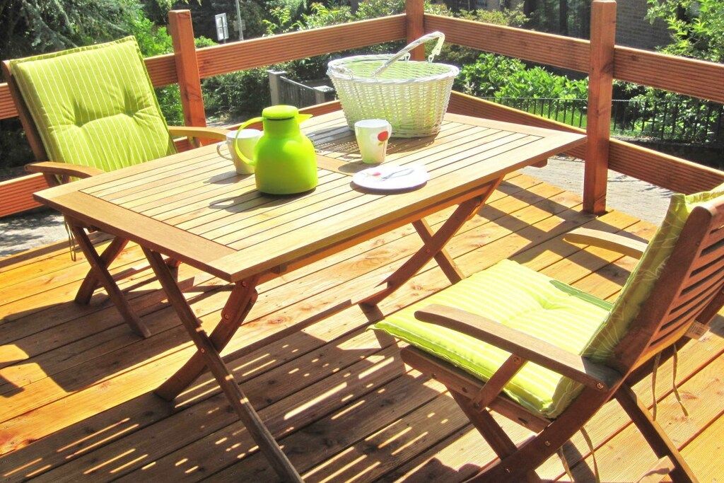A wooden deck with a table and chairs, a basket, and a green bottle.