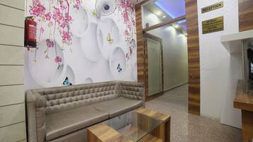 A reception area with a sofa, a glass table, and a wall with floral and butterfly decorations.