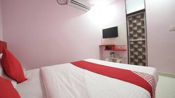 A bedroom with a bed, a flat-screen TV mounted on the wall, and a small table with a coffee maker.