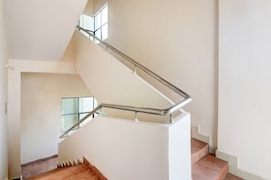 Eine Treppe mit Metallgeländer, Holzboden und weißer Wand.