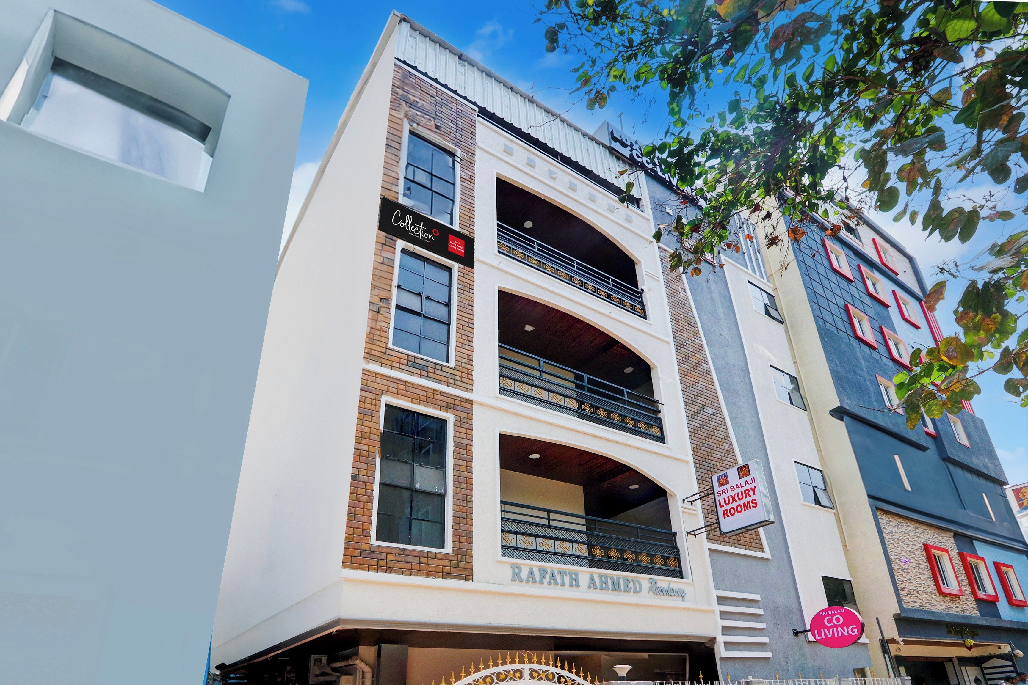 A multi-story building with a sign for 'Sri Balaji Luxury Rooms' and another sign for 'Collection.'