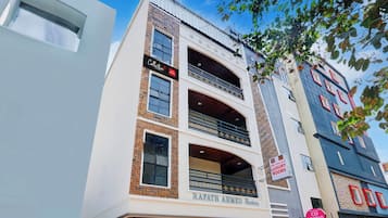 A multi-story building with a sign for 'Sri Balaji Luxury Rooms' and another sign for 'Collection.'