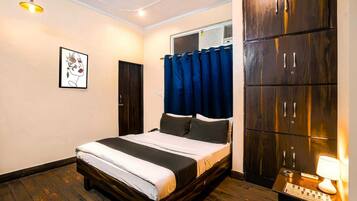 A bedroom with a bed, a wardrobe, a ceiling fan, a wall-mounted air conditioner, and a framed artwork.