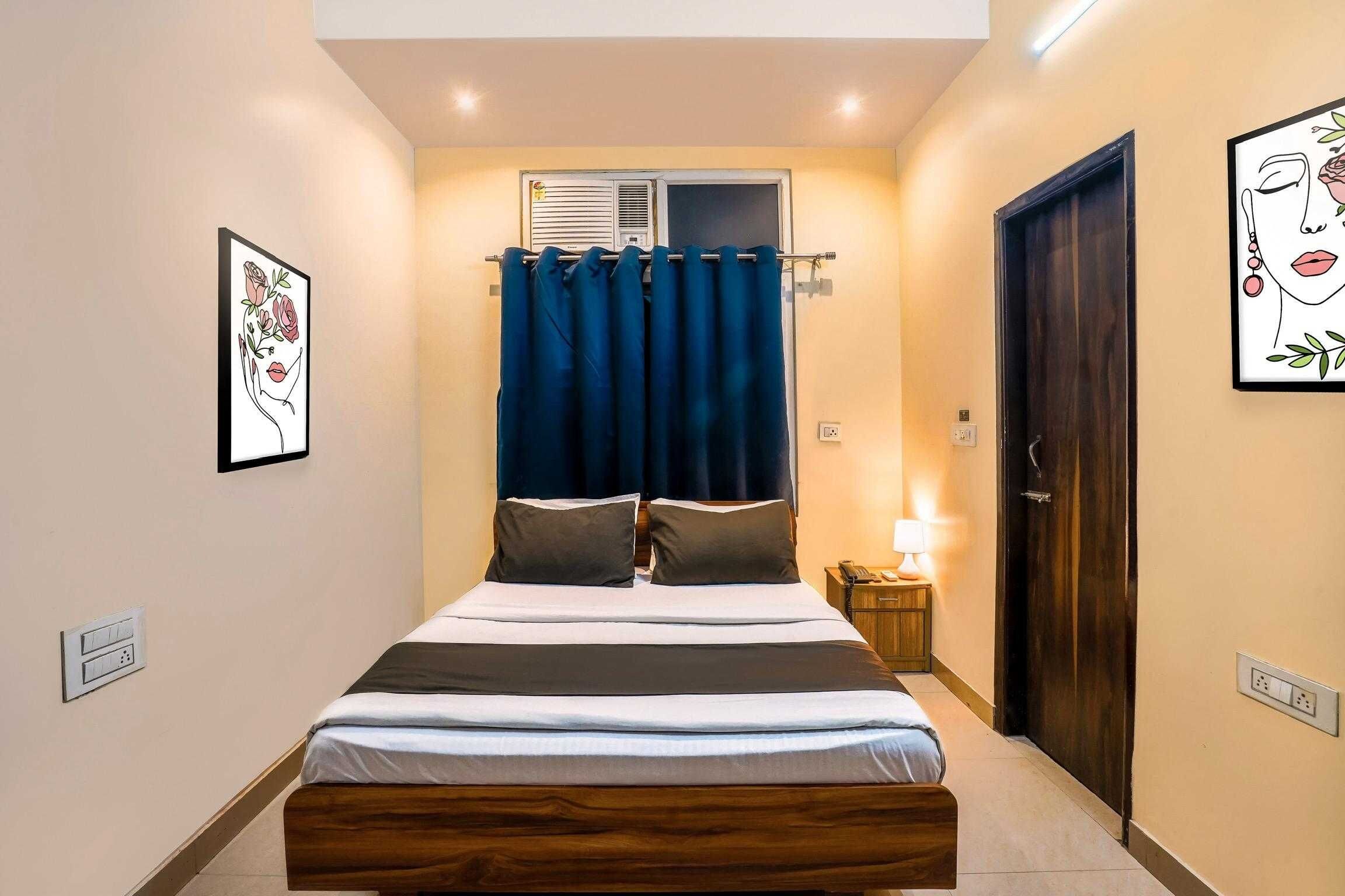 Un dormitorio con cama, cortinas, una mesita de noche, una lámpara y una puerta.