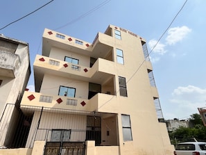 Um edifício com várias andares, varandas, entrada fechada por portão e um letreiro com a inscrição 'SILVER PARADISE'.