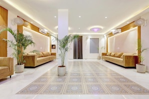 Sala de estar moderna com dois sofás, um pilar central e plantas em vasos.