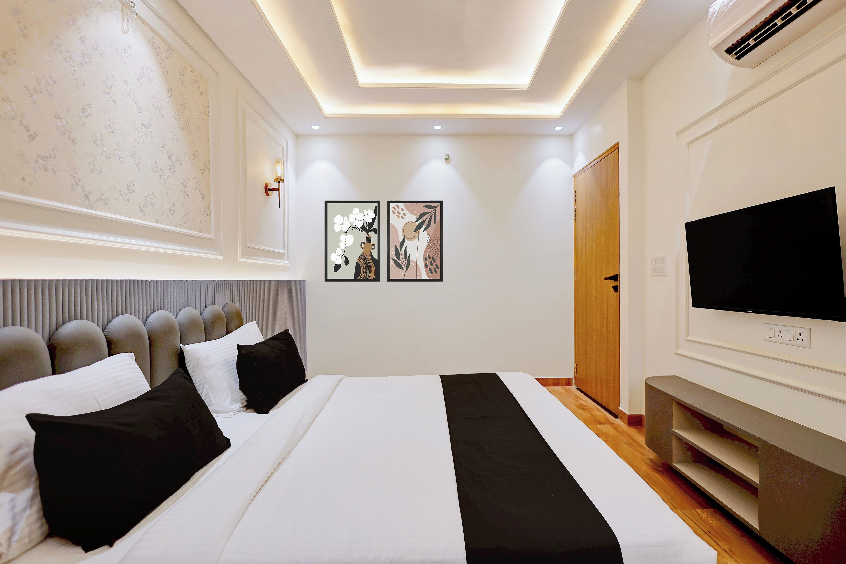 A modern bedroom with a large bed, a flat-screen TV, and a wooden wardrobe.