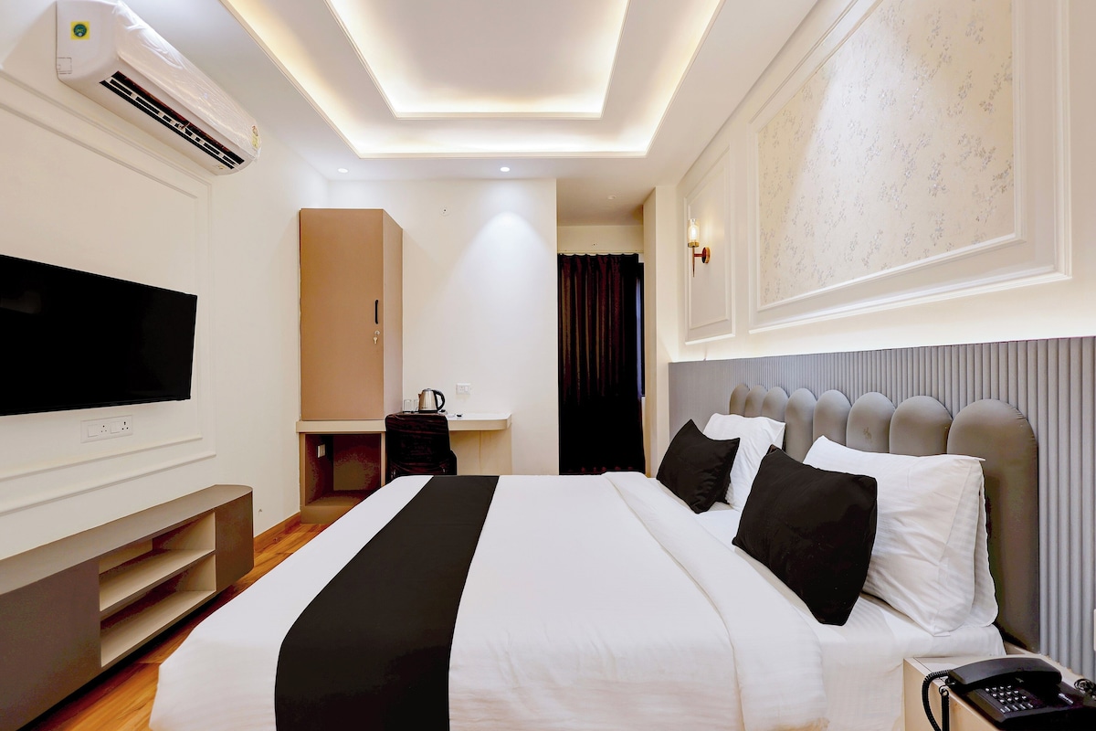 Una camera d'albergo con un letto grande, una scrivania, una televisione e un telefono.