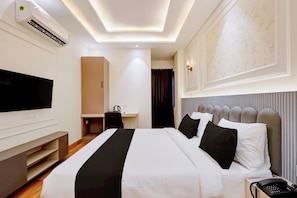 Una camera d'albergo con un letto grande, una scrivania, una televisione e un telefono.