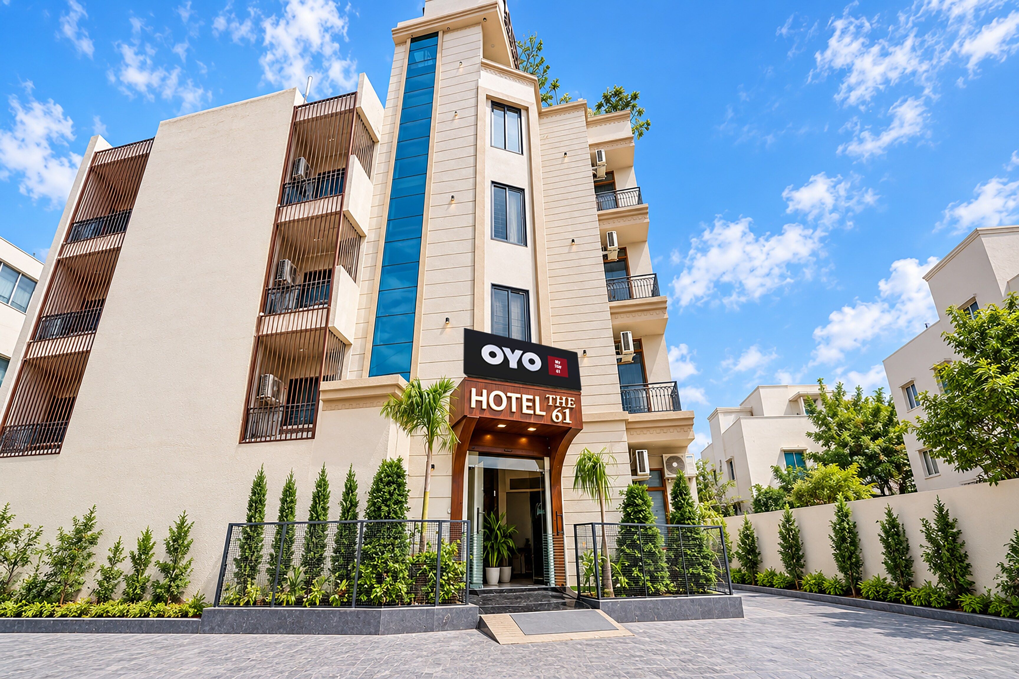 A hotel building with a prominent blue vertical feature, a sign reading 'OYO HOTEL THE 61', and a gated entrance.