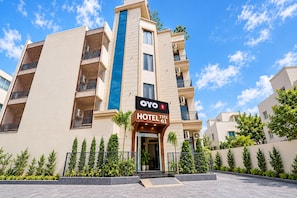 Edifício de hotel com uma característica vertical azul destacada, uma placa com a inscrição 'OYO HOTEL THE 61' e uma entrada com portão.