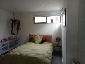 Una camera da letto con un letto, un comodino, una finestra e un termosifone.
