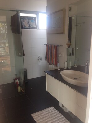 A bathroom with a glass shower enclosure, a white sink, and a towel rack. -  A WONDERFUL TOWNHOUSE THAT IS ONE MINUTE FROM THE BEACH AND CENTRAL TO SHOPS. (Elwood)