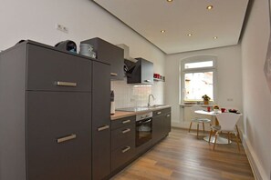 A modern kitchen with built-in appliances, a dining area with a round table and chairs, and a window providing natural light. - Holiday apartment in Erfurt with barbecue (Erfurt)