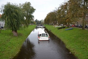 Ein schmaler Kanal mit einem Boot, umgeben von Bäumen und Gebäuden.