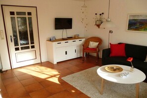 A living room with a television, a sofa, a coffee table, and a cabinet. - Holiday home in Tönning with swimming pool (Tönning)