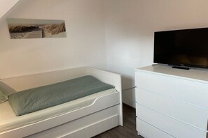 A bedroom with a single bed, a dresser, and a television on a stand. - Seepark Burhave House 33 (Butjadingen - Burhave)