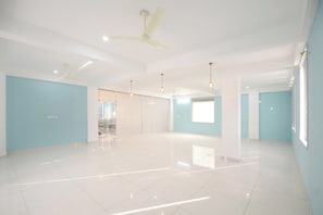 Una habitación amplia con techo alto, paredes blancas y un ventanal grande.