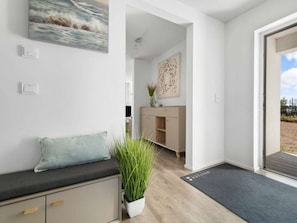 Ein modernes Interieur mit einer Bank, einem Blumentopf und einer Tür, die zu einem Außenbereich führt.
