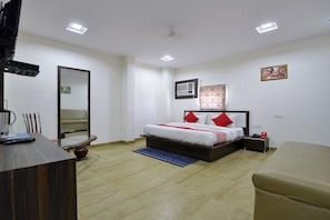 Ein Hotelzimmer mit Bett, Nachttisch, Spiegel und kleinem Schreibtisch mit Stuhl.