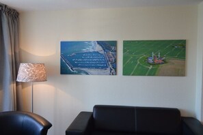 A room with a black leather sofa, a lamp, and two paintings on the wall. - Holiday apartment Strandschlösschen 319607 (Kühlungsborn)