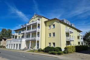 A multi-story hotel with balconies, a covered entrance, and a parking area. - Holiday apartment Strandschlösschen 319607 (Kühlungsborn)