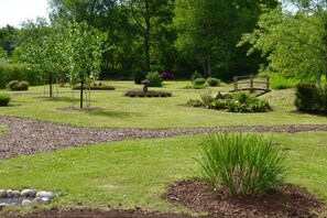 A well-maintained garden with a variety of plants, a wooden bridge, and a stone pathway. - Holiday home with 2 bedrooms (Papenburg)